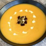 squash soup with garnish in black bowl