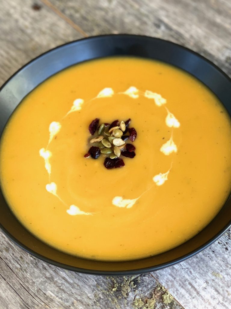 squash soup with garnish in black bowl