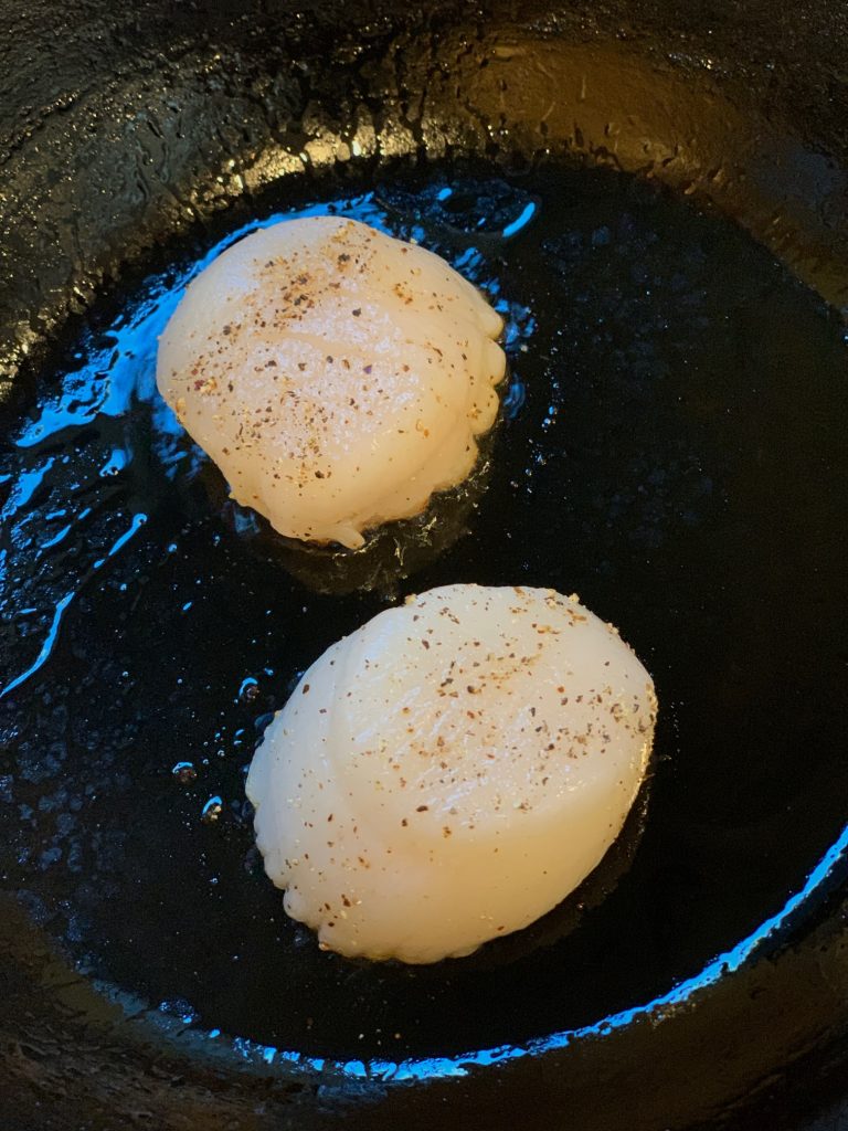 Scallops beginning to sear in cast iron