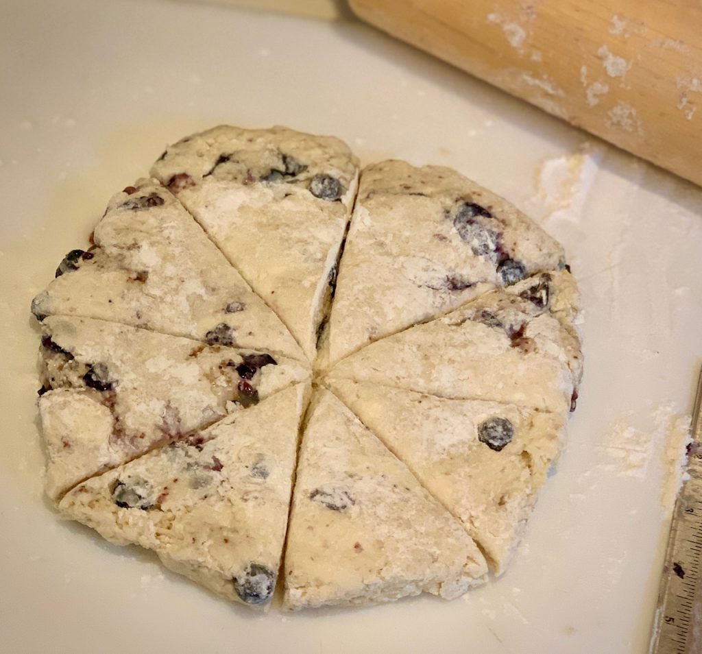 Blueberry scone dough cut into triangle and rolling pin triangles