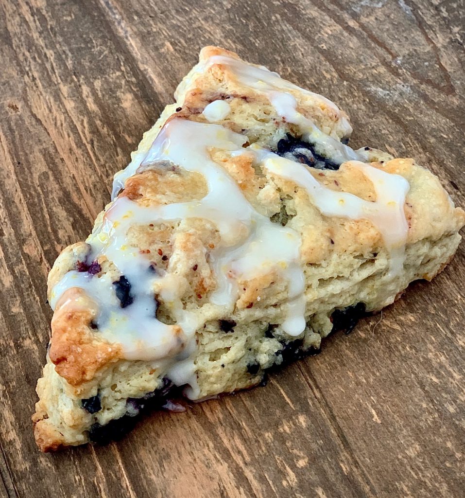 Blueberry scone with lemon icing on wood board