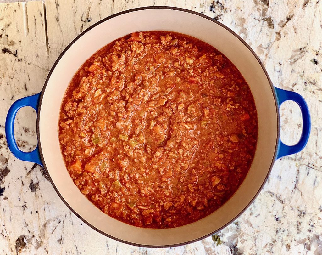 Bolognese Sauce in a blue pot on white marble