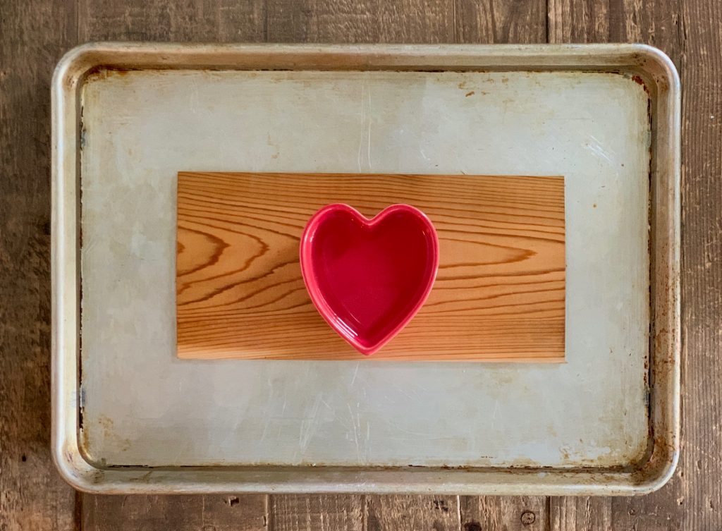 Cedar plank soaking in water on a tray