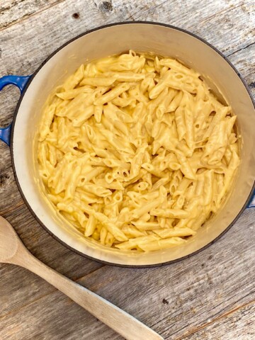 Mac and cheese in a blue pot with wooden spoon