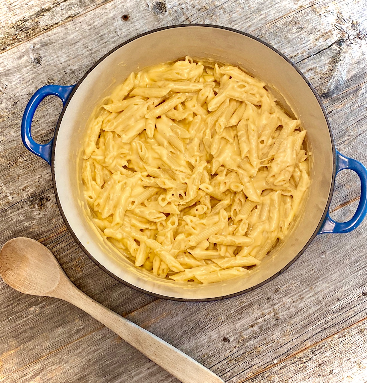 Mac and cheese in a blue pot with wooden spoon