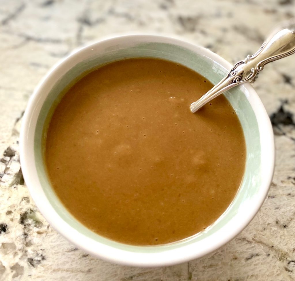 Peanut sauce in a bowl on white granite with a spoon