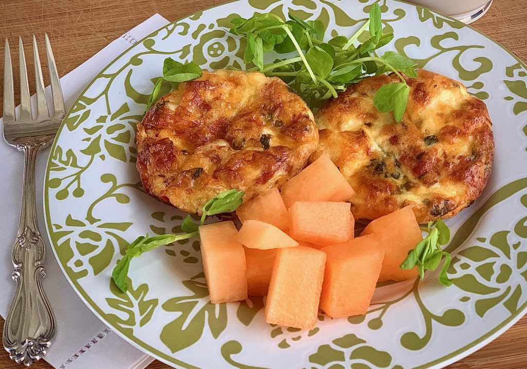 quiche on a plate with salad and cantoloupe