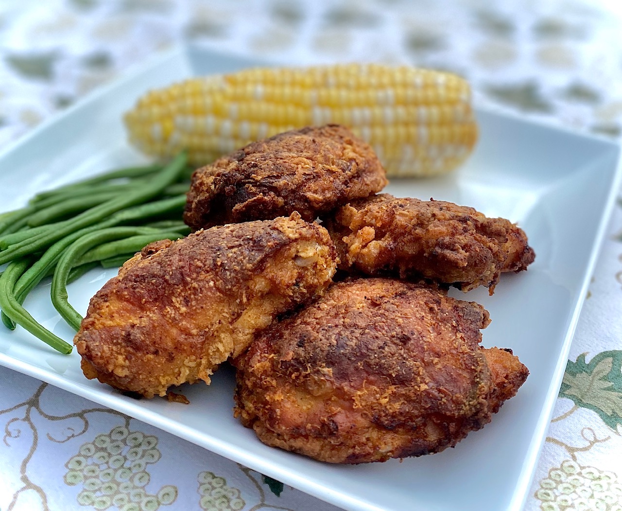 a platter of fried chicken with corn and beans