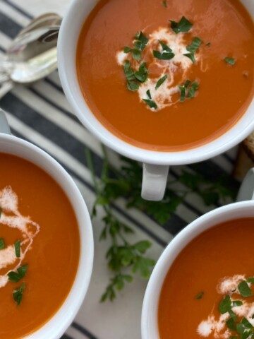 3 bowls Roasted Tomato Soup with spoons and garlic bread