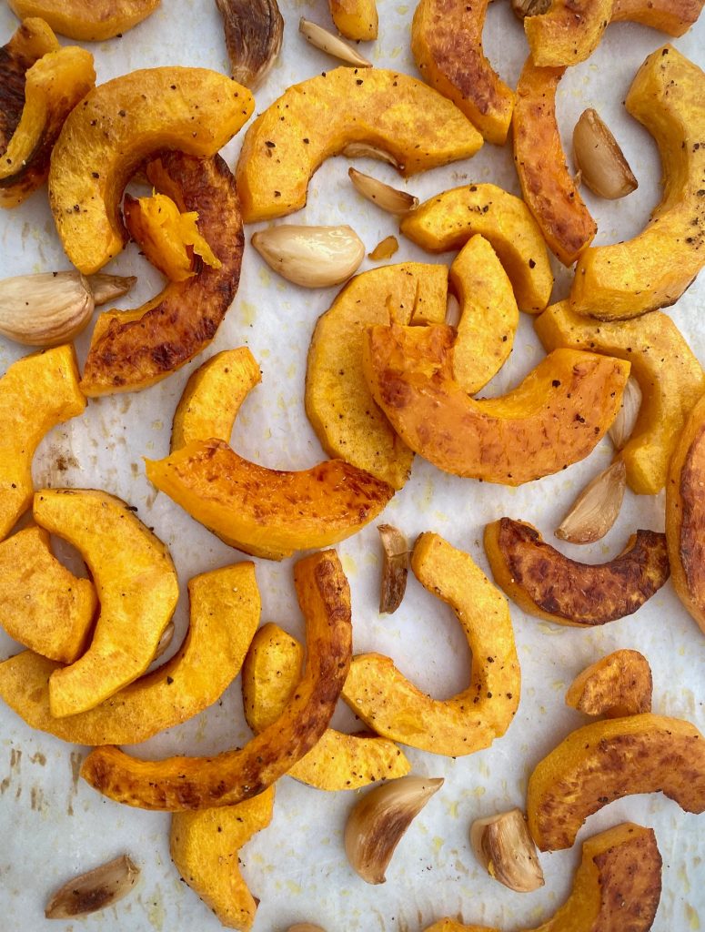 Roasted butternut squash and garlic on a baking sheet