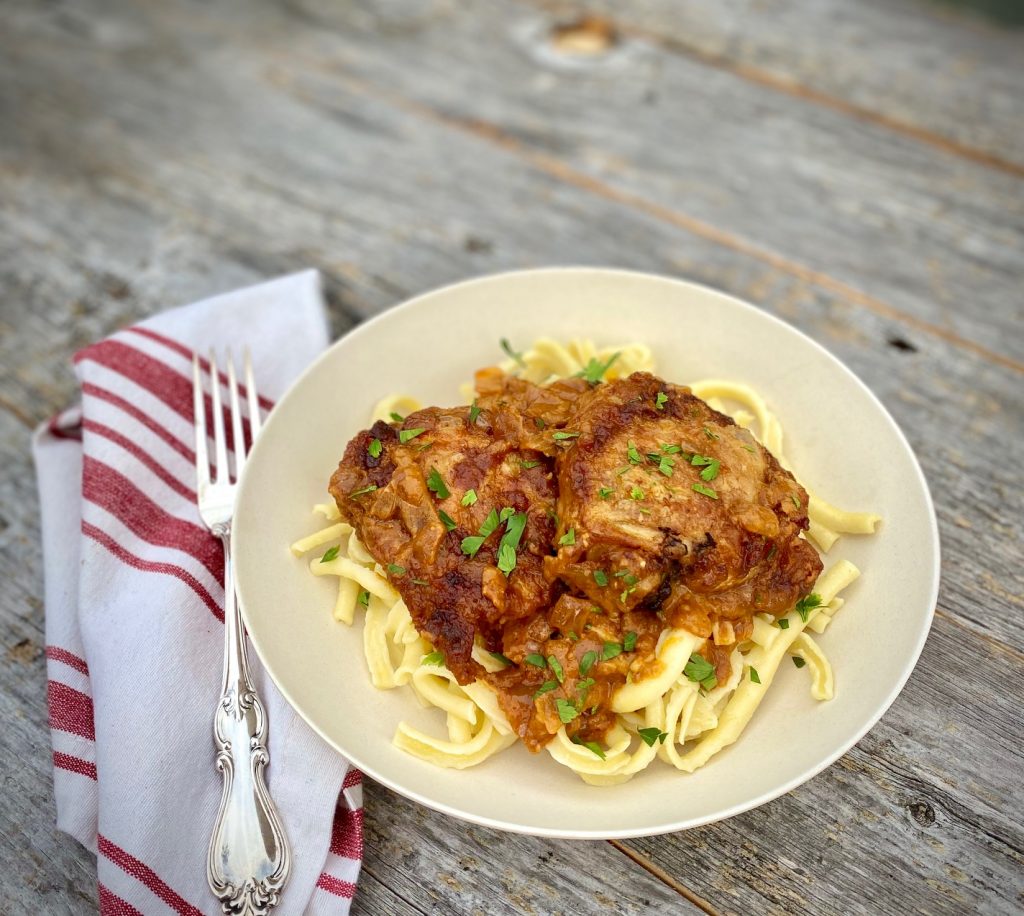 Chicken Paprikash over noodles in a bowl with a fork