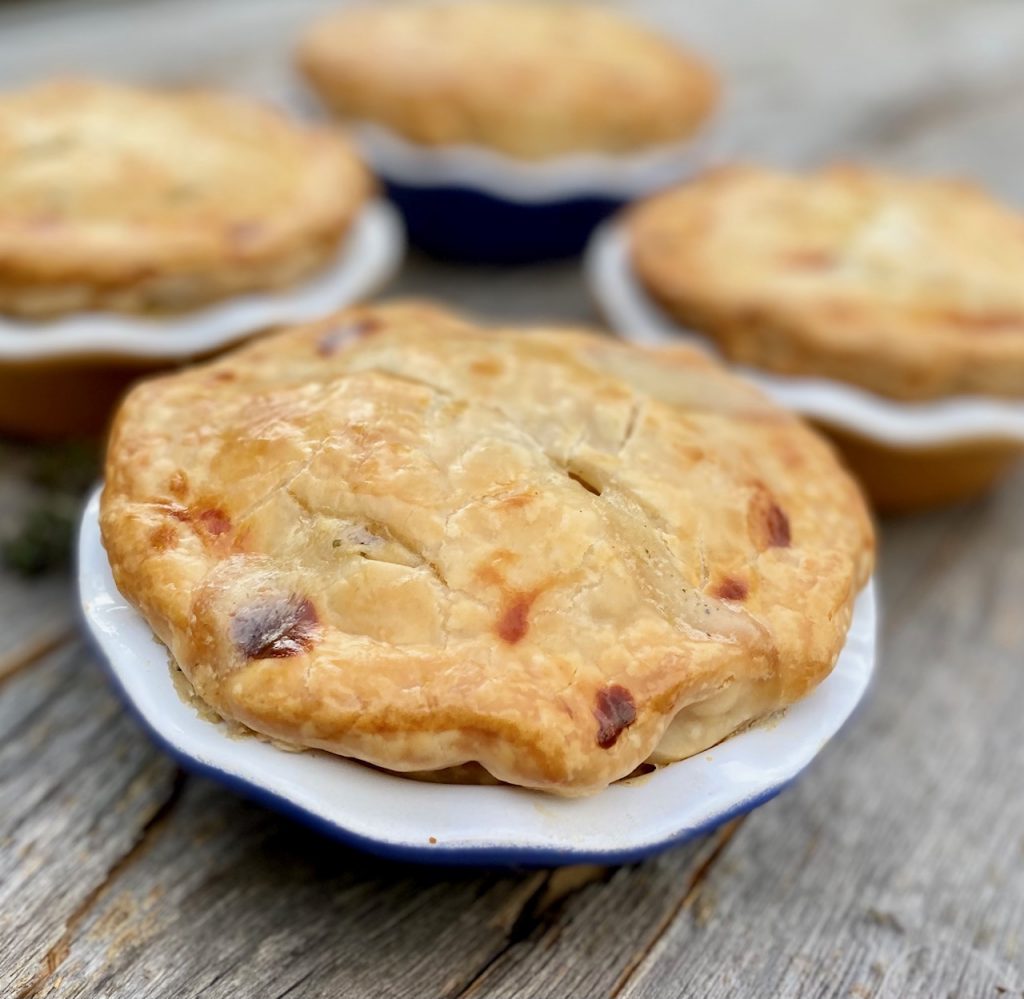 4 pot pies close up on a wood board