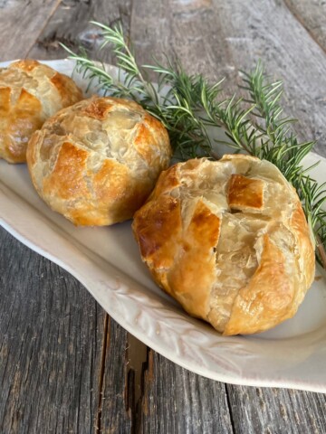 3 individual beef wellingtons on a white platter