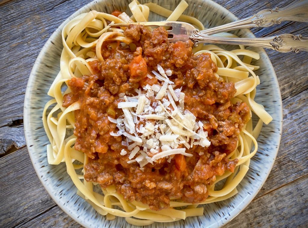 classic bolognese with fettucine in a blue bowl