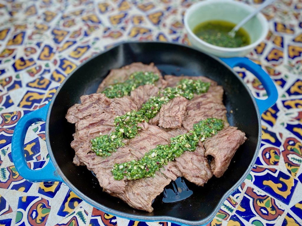 steak with chimichurri sauce in a blue grill pan