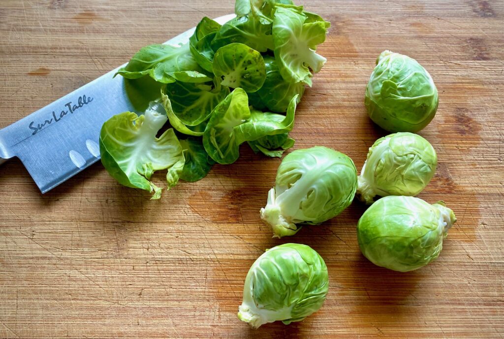 fresh brussel sprouts on a cutting board with a knife