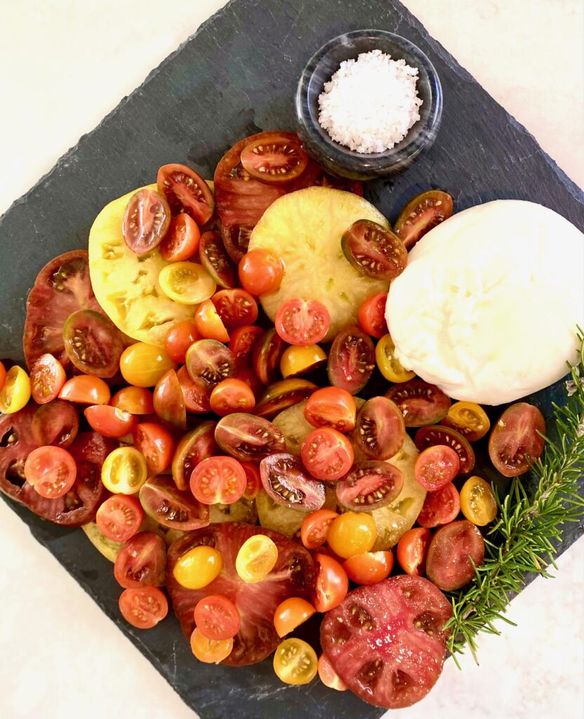 black slate platter with tomatoes, cheese and salt