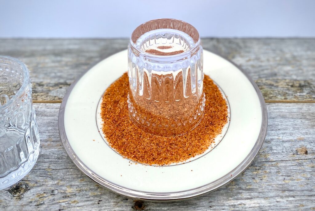 upside down glass in a plate of Tajin seasoning