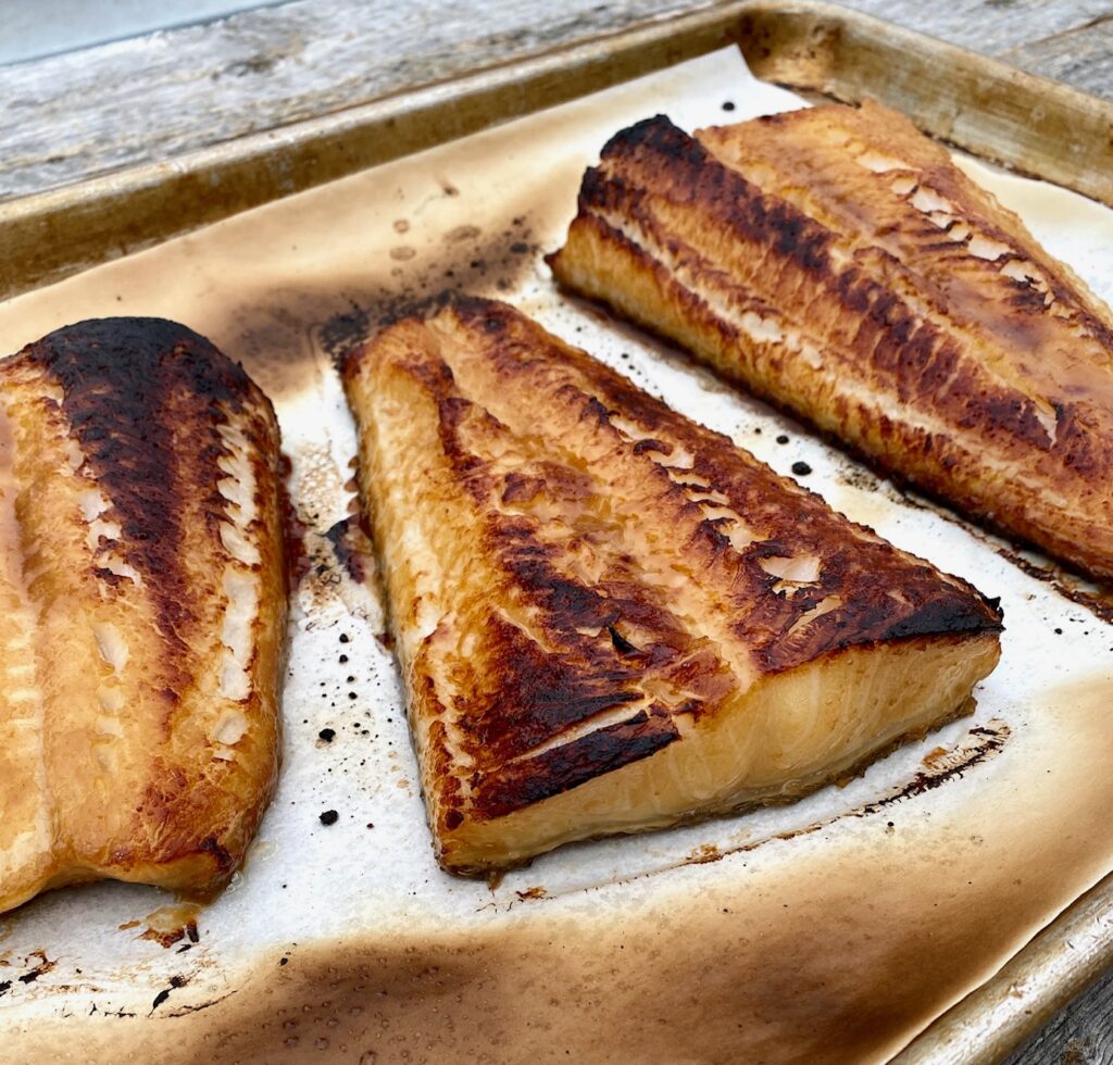 3 pieces of broiled sea bass on a baking sheet