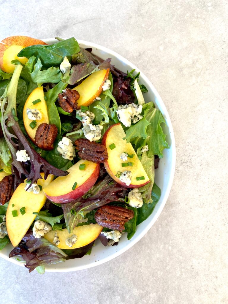 a peach blue cheese salad in a white bowl