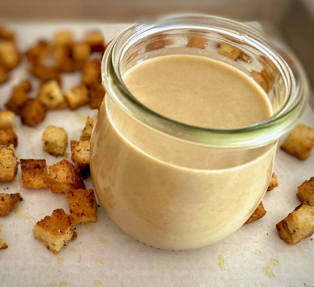 salad dressing in a jar next to a bunch of croutons