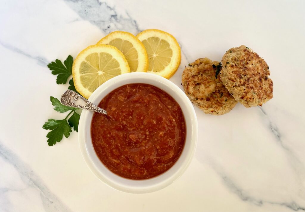 crab cakes, bowl of sauce and lemon