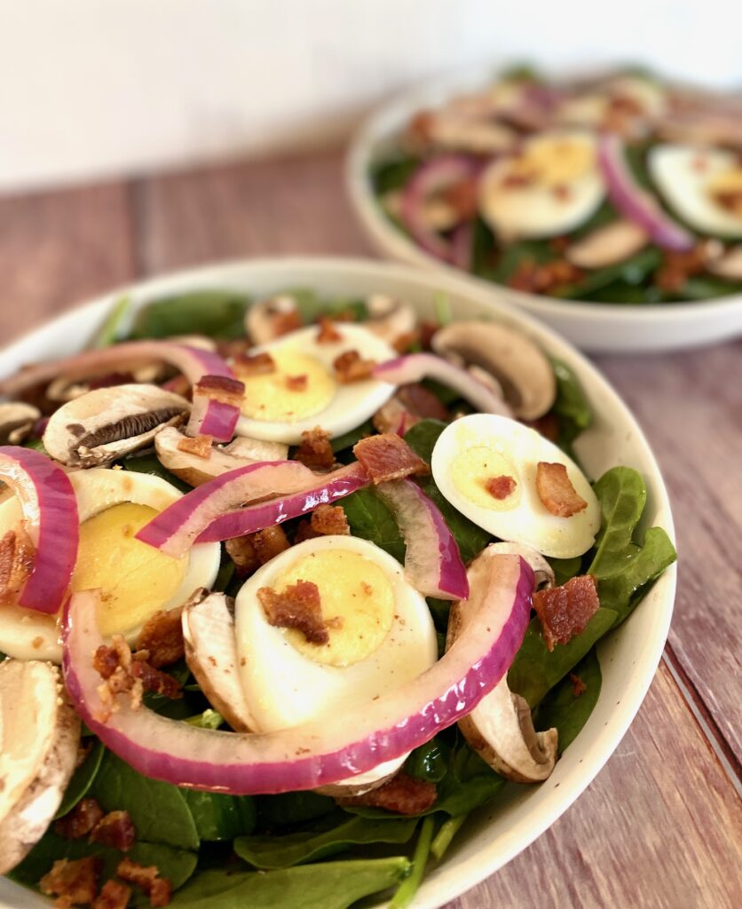 a bowl of spinach bacon salad