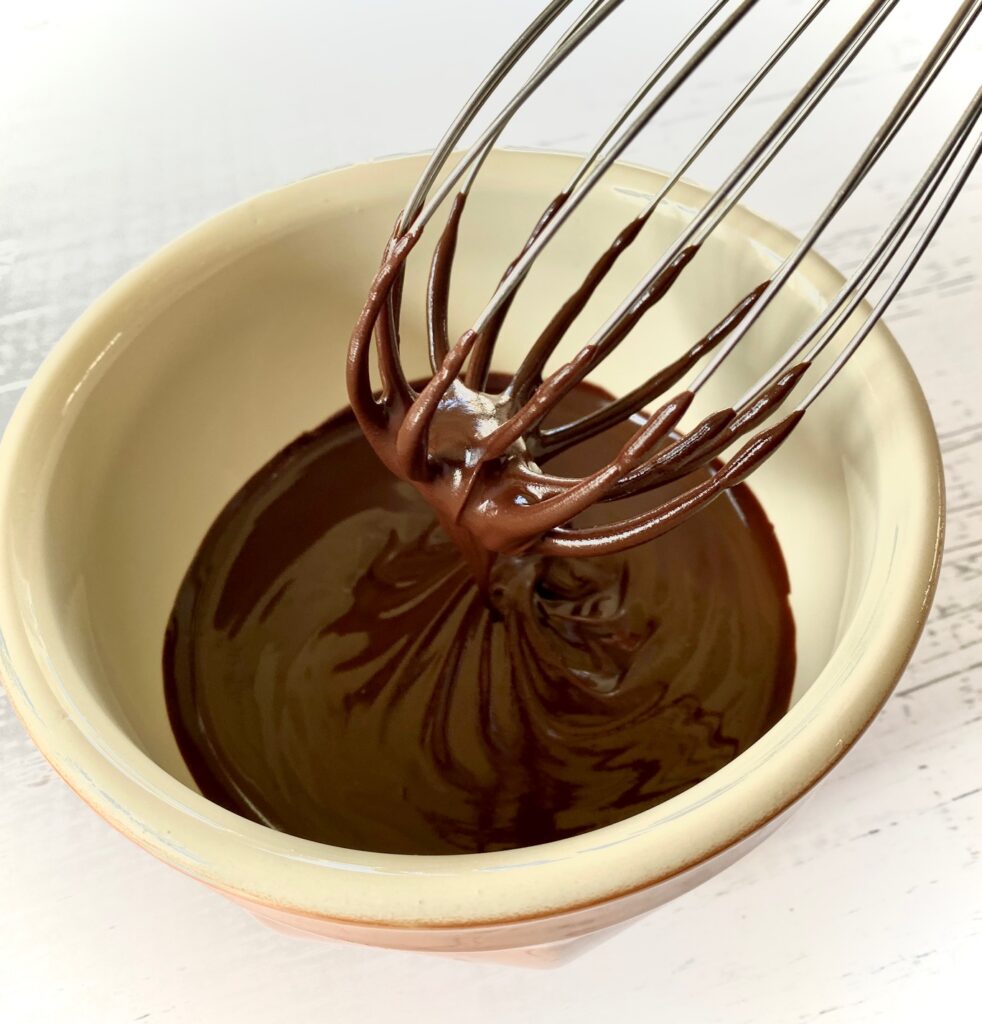 Melted chocolat in bowl with a whisk