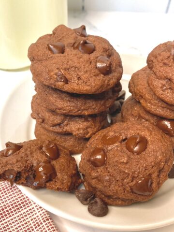 A Stack of Double Choc Cookies with milk on white plate