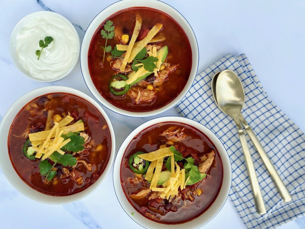 3 bowls of soup with garnishes and spoons