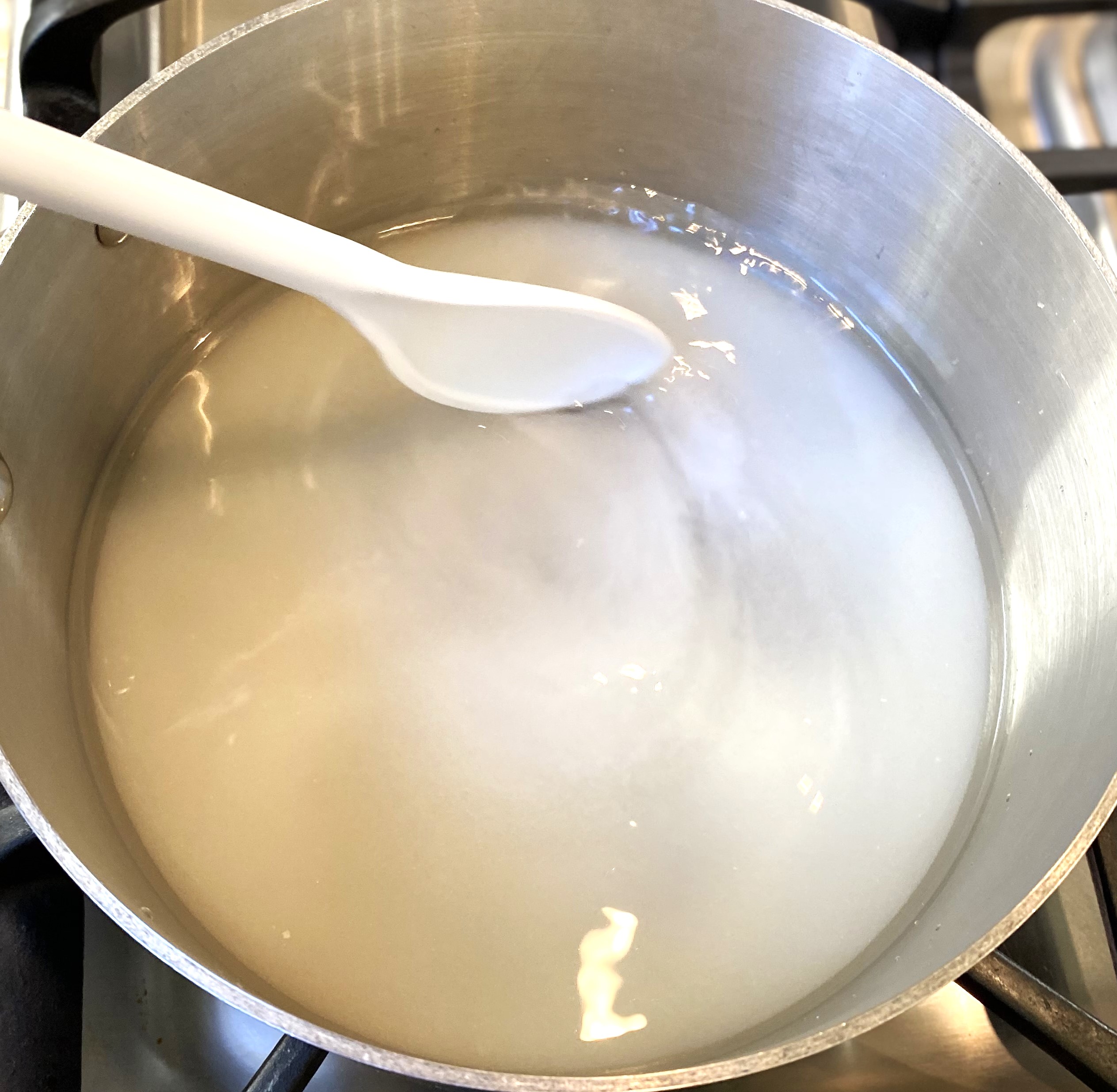 spoon stirring pan of sugar water