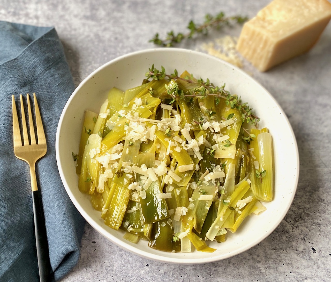 Braised leeks with parmesan cheese in white bowl