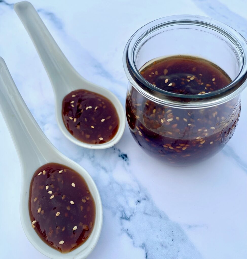 a bottle of sauce with 2 spoons