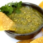 Verde Salsa with a chip in black bowl