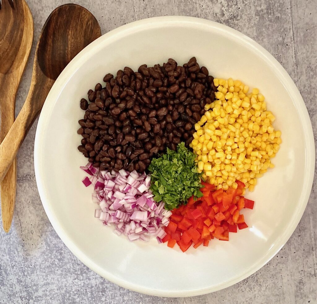 bowl of ingredients containing onion, red pepper, corn, black beans, cilantro
