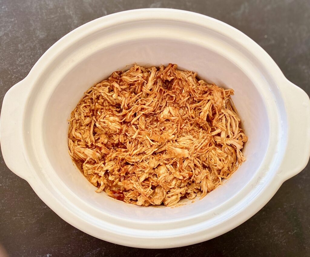 a white crockpot bowl with bbq chicken