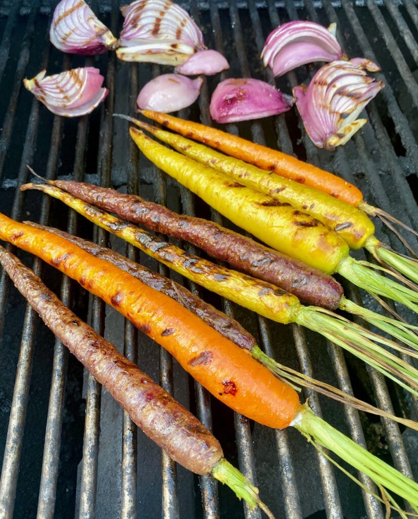 grilled organic carrots and red onions on grill grates