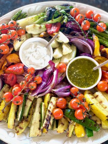 a platter of roasted vegetables with dipping sauces