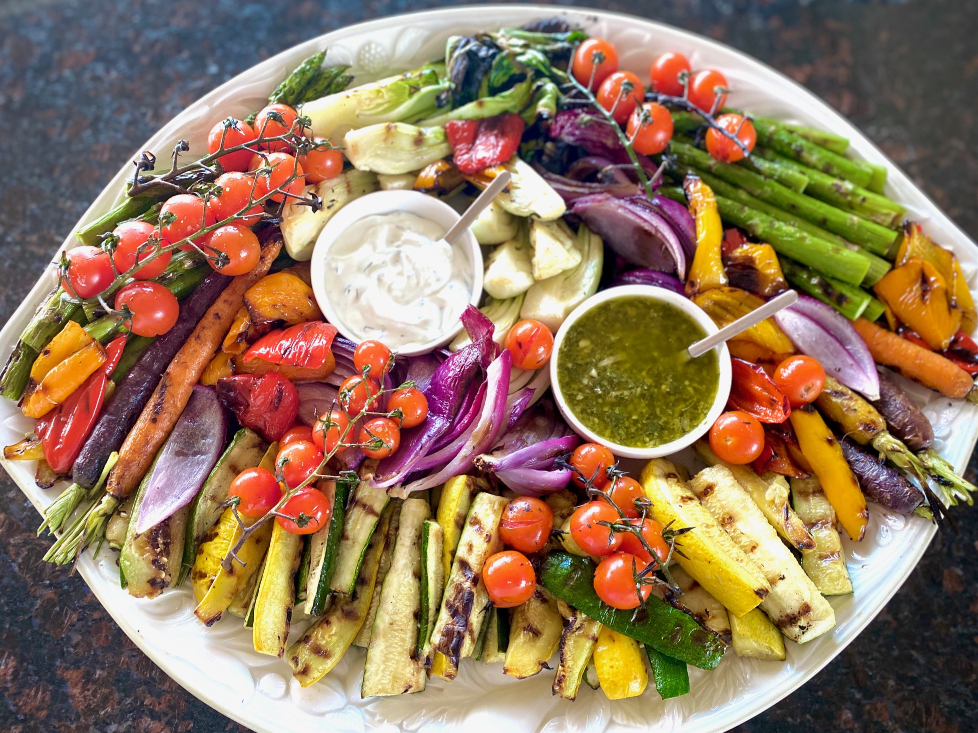 a platter of roasted vegetables with dipping sauces