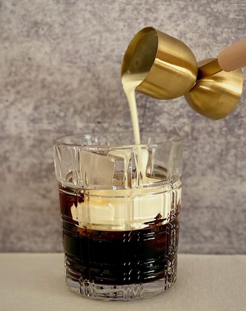 pouring cream into a kahlua cocktail