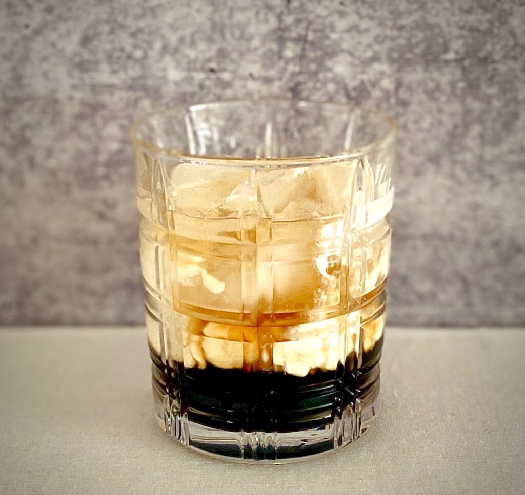 a glass of ice with whiterussian drink
