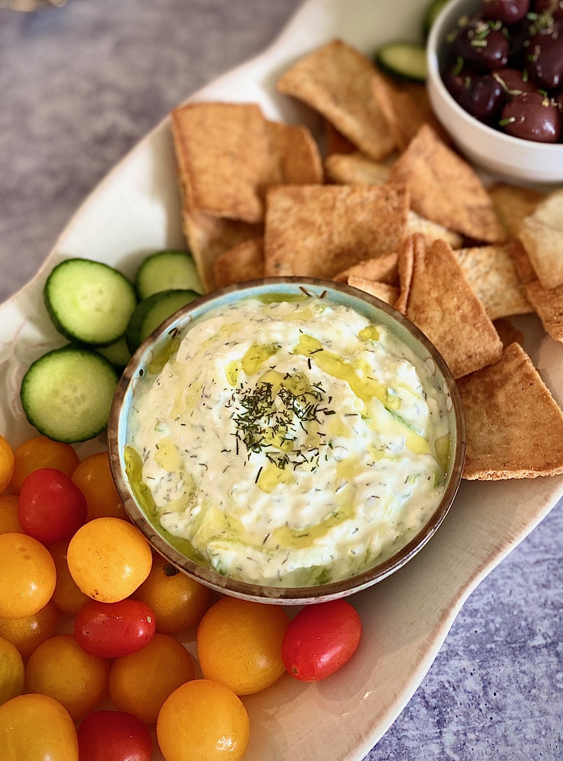 platter of tzatiki with tomatoes, crackers.