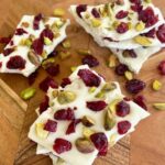 cranberries, pistachios and chocolate on a board