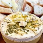 a round of cheesey melted brie with bread and crackers