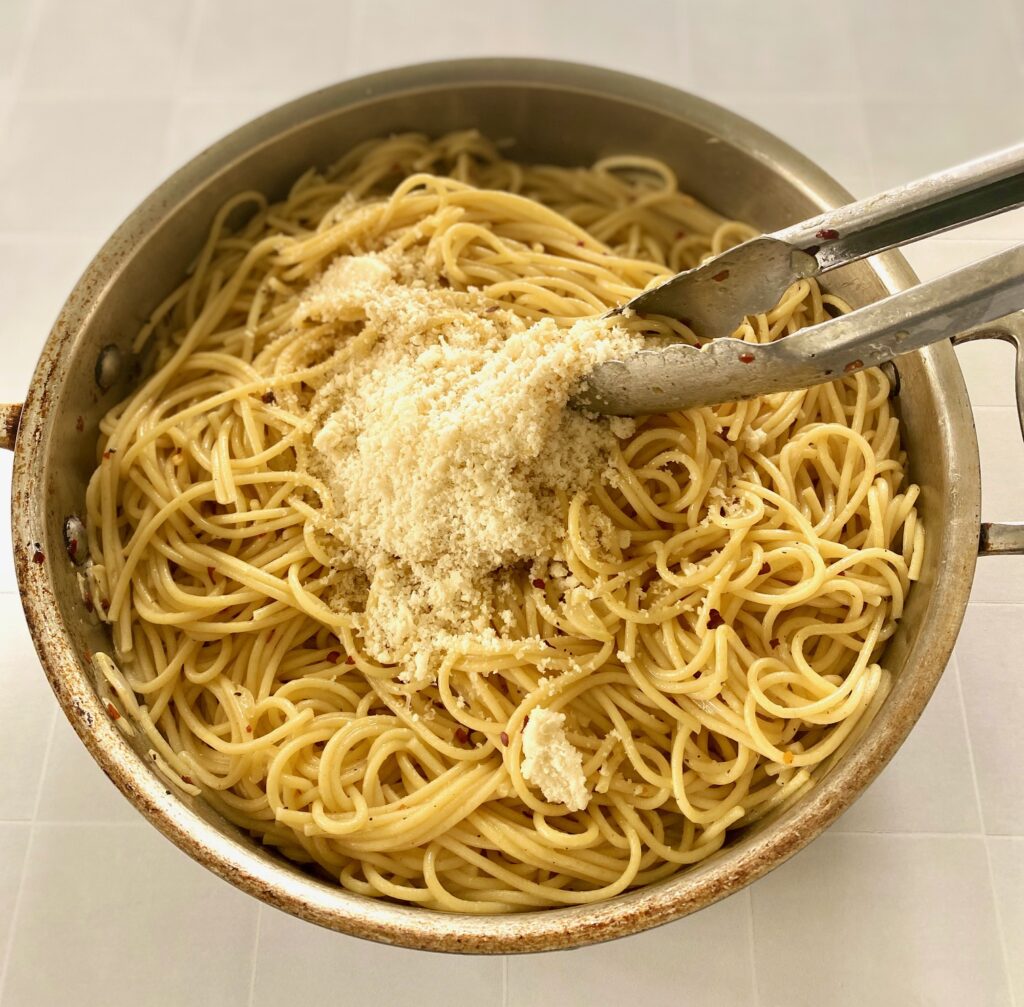 grated parmesan on top of pan of spaghetti