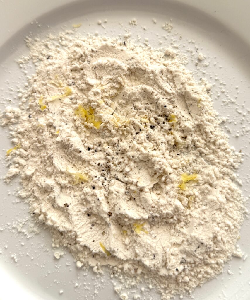 flour with zest, salt and pepper on a white plate