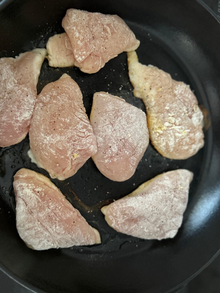 sauteeing chicken breasts in a black pan
