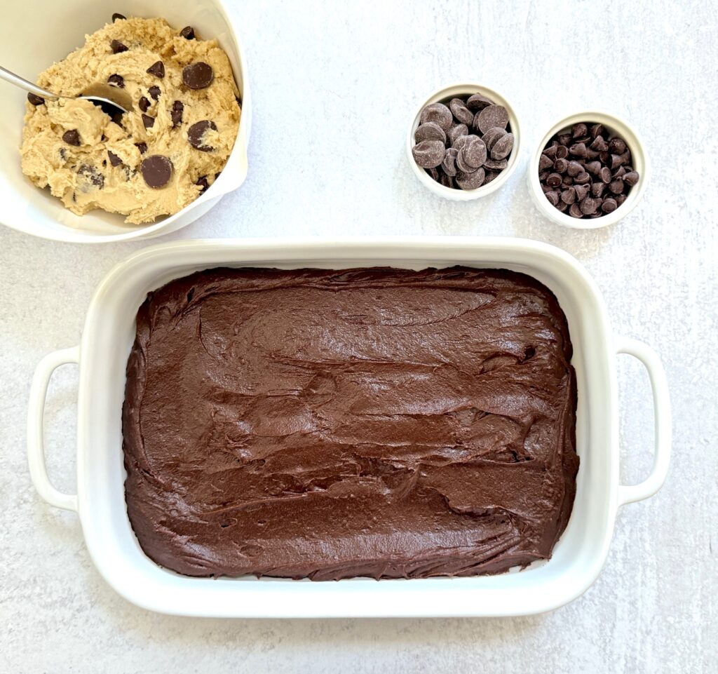 brownie mix in pan with bowl of chocolate chip dough