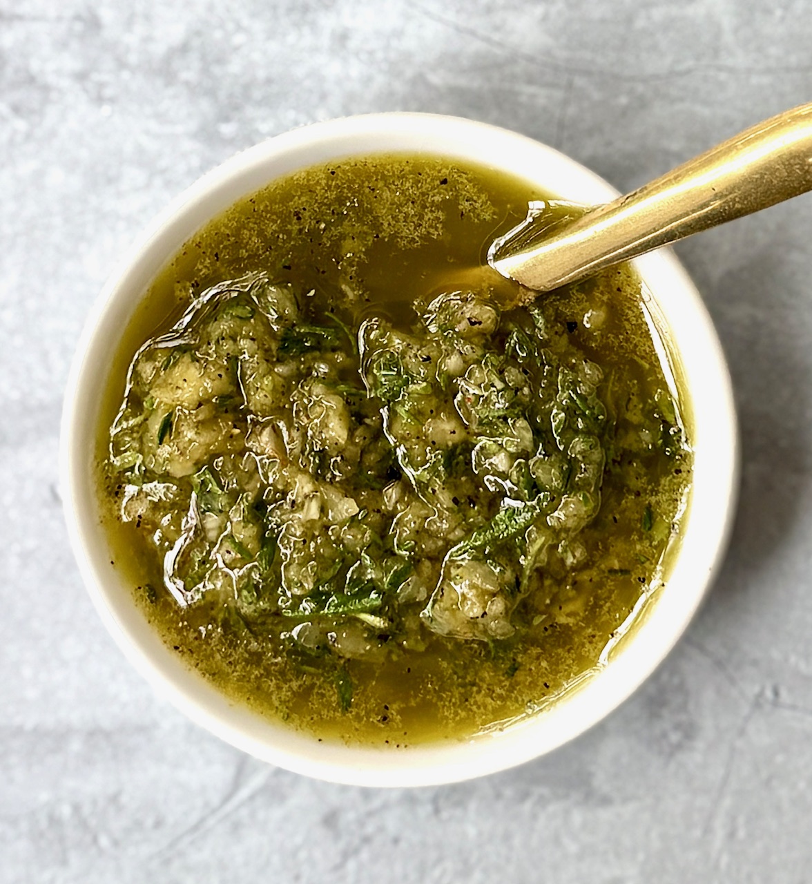 beef rub paste in white bowl with a gold spoon
