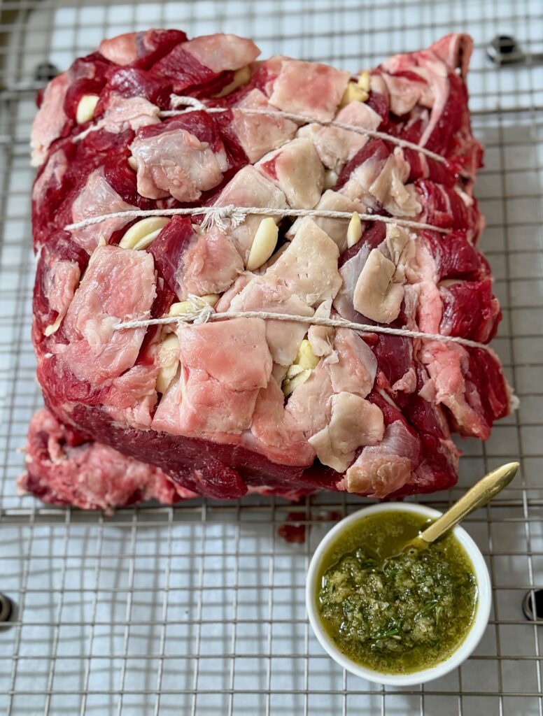 uncooked rib roast on a rack and garlic rub in a white bowl